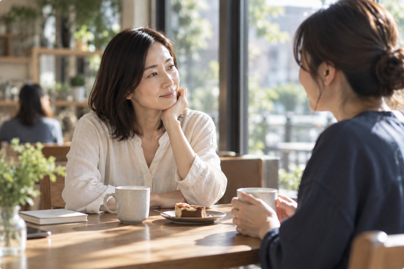 カフェで向かいの相手と穏やかに話している女性